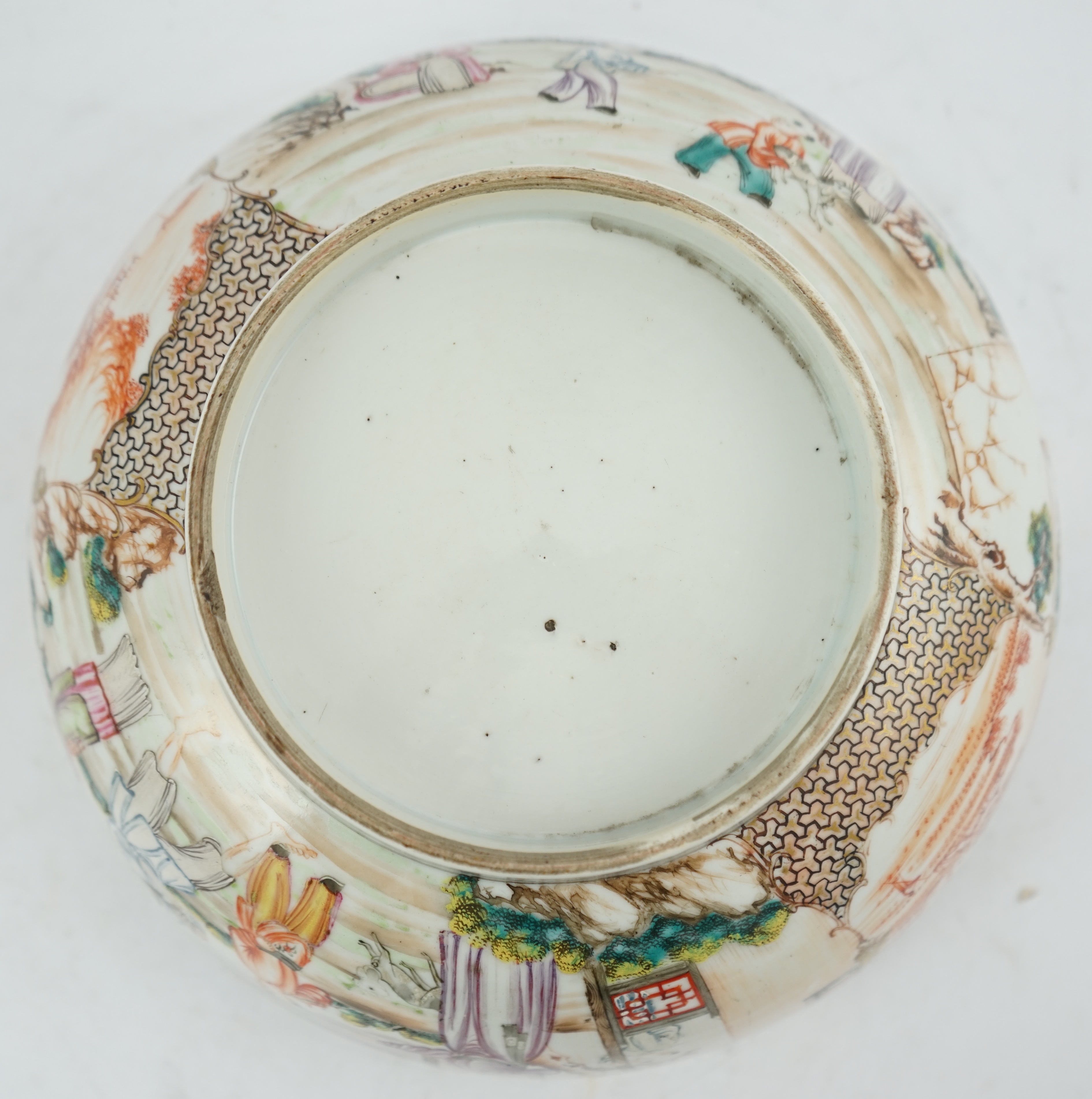 A Chinese famille rose ‘mandarin’ bowl, Qianlong period, painted with figures in a lakeside garden, between red enamelled landscape vignettes and cellular panels, 28.4cm diameter. Condition - there is a hairline crack to